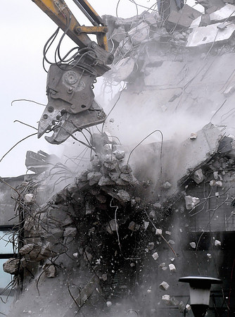 Bits of concrete falling from the jaws of the digger